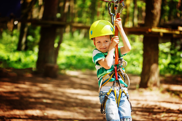 Adventure climbing high wire park – little child on course in mountain helmet and safety equipment