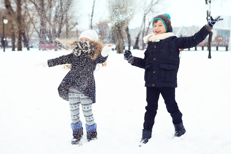 boy and girl having fun with the snow in winter park