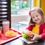 Little girl eating a hamburger in fast food restaurant