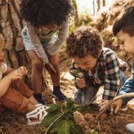 Kids exploring in forest with a magnifying glass