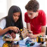 Two Students In After School Computer Coding Class Building And Learning To Program Robot Vehicle