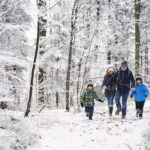 Father with kids running in beautiful winter forest