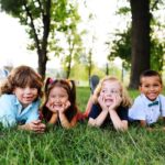 friends of preschool kids playing lying on the grass in the Park on a summer day