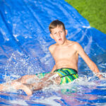 Teen boy sliding down a slip and slide outdoors