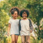 Happy little boy and girl in the park. Two African American children together in the garden.