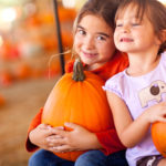 Cute Little Girls Holding Their Pumpkins At A Pumpkin Patch One Fall Day.