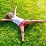 Smiling Little Girl Lying On Grass Meadow