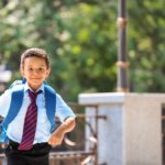 Cute African-American schoolboy running outdoors