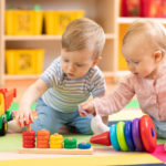 Preschool boy and girl playing on floor with educational toys. Children at home or daycare.