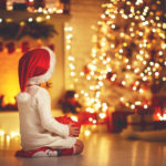 child girl  sitting  back in front of  Christmas tree on Christmas Eve