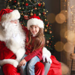 Santa Claus and little girl in room decorated for Christmas