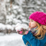 Cute little girl blows snow from hands