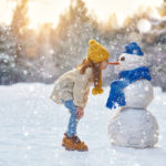 girl playing with a snowman