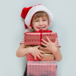 Happy child in Santa red hat holding Christmas present. Christma