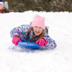 Girl Sledding Head First and Looking at Camera