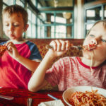 kids eat pizza and pasta at cafe. children eating unhealthy food