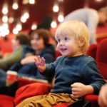 Cute toddler boy watching cartoon movie in the cinema