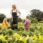 Young mother standing in a vegetable garden with her children