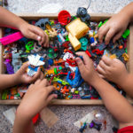 The hands of many children who are playing toys together.