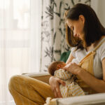Newborn baby boy sucking milk from mothers breast. Portrait of m