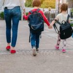 Back to School of Mother and pupil and kids holding hands going