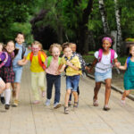 small schoolchildren with colorful school bags and backpacks run to school. Back to schoo