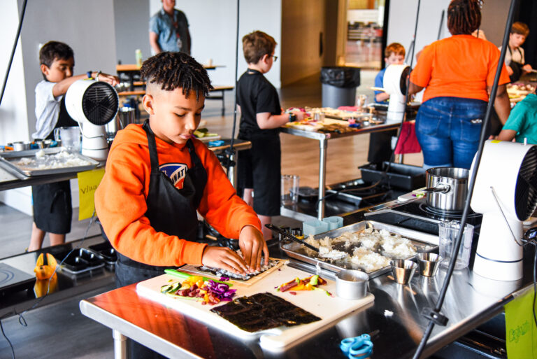Local Spotlight: Cincinnati Museum Center Cr(EAT)e Culinary Studio A kitchen is so much more than a place to prepare food. New to Cincinnati Museum Center is the Cr(EAT)e Culinary Studio, a versatile programming space featuring the Kroger Food Lab, with multiple cooking stations, including ovens and ranges. Southwest Ohio Parent spoke to Cody Hefner, vice president of marketing & communications for the Cincinnati Museum Center, to learn more about this culinary space.  What inspired the Cr(EAT)e Culinary Studio?  The idea started as a food science lab, but evolved into a vision of a versatile space where food, science, history and community can come together. The museum is already a place where science, history and early childhood development converge, so we decided to put a food lens around that.  How can museum visitors use the studio?  We’re developing programming for the space that will allow 20 to 30 people — kids and adults — to chop, whisk, bake and sauté their way through classic and experimental recipes, while also diving into the science and history behind them. Our first programs are available now, with more on the way in spring 2024.  We’re also planning week-long Museum Camps this summer. We tested them last year and had an amazing response. Kids 10, 11 and 12 years old made their own sushi, pasta and alfredo from scratch, and baked and decorated cakes. It was incredible. You’ll also see mini demonstrations pop up in museum spaces through a cart program, and we’re having a lot of fun incorporating the Cr(eat)e Culinary Studio into theme days and events.  Will you be working with local chefs and industry experts?  We’ve engaged a range of partners and are continuing to do so as we build out programs, demonstrations and other learning opportunities. For example, we’ve partnered with nonprofit LaSoupe Cincinnati on some research and program development, as well as the University of Cincinnati.  How can people support the Cincinnati Museum Center and the studio? Come cook with us! We’re developing more and more programs and are excited to launch our spring schedule soon, as well as the opportunities for our Museum Camps this summer.  And think more about your food at home. Where does it come from? What recipes can you pass on? What tweaks can you make to be your own culinary mad scientist?   SIDEBAR Cr(EAT)e Culinary Studio Upcoming Events Science by the Bite: Homeschool Cooking Club for ages 7 to 14 French Toast & Compote: December 7 Mac and Cheese: January 18 Muffin Mix-up: January 25  Junior Chefs: Parents & Children Cooking Together Cake and Ice Cream: January 13 Amazing Alfredo: January 20 Learn more about upcoming programs and register online at cincymuseum.org/create-culinary-studio. The CMC is cooking up something good that will get kids into the kitchen.