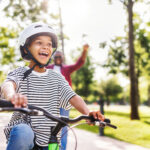 Happy family father teaches child  son  to ride bike in park