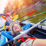 Happy kids kayaking on the river on a sunny day during summer vacation