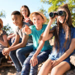Group of children with binoculars outdoors. Summer camp