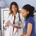 African American patient explaining issues to Asian doctor using tablet