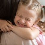 Funny cute little girl smiling embracing foster care parent mum