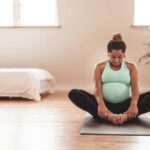Beautiful expectant mother doing yoga at home