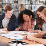 Group Of College Students Collaborating On Project In Library