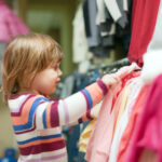 baby girl  chooses clothes at shop