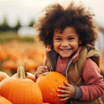 Happy child in a pumpkin patch in autumn. Halloween seasonal fall. Laughing toddler in October. Smiling kid.