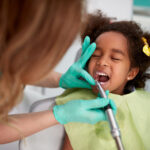 Female dentist patiently polish teeth to child