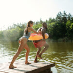 Happy friends having fun, jumping and swimming in river
