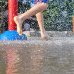 On a hot summer day, children are running around in the city’s water splash pad playground.