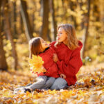 Mother and daughter sitting on a blanket in autumn forest
