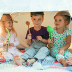 Cute little children playing with kitchenware while sitting in hovel at home