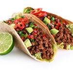 Mexican tacos with beef, tomatoes, avocado, chilli and onions is
