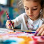 Student Painting at Colorful Table in Sunlit Classroom with Hand and Brush perfect for art education brochures, creative learning campaigns, afterschool program promotion and school websites