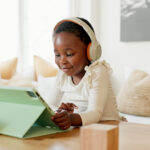 Language learning, headphones and black child with tablet for online education translation website or video call. Relax kid with digital technology listening and speaking for online learning games